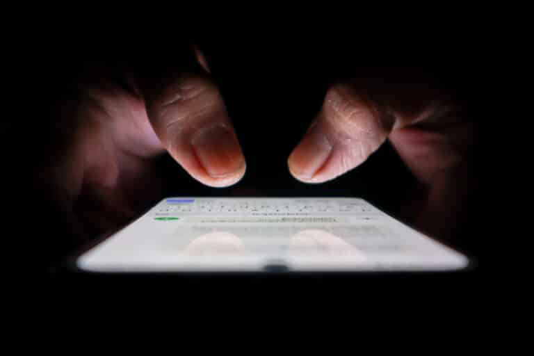 Night, cybersecurity and hands typing with phone for texting, internet troll or person cyberbullying. Dark comment, social media netizen or keyboard warrior for smartphone, online bullying or hacking